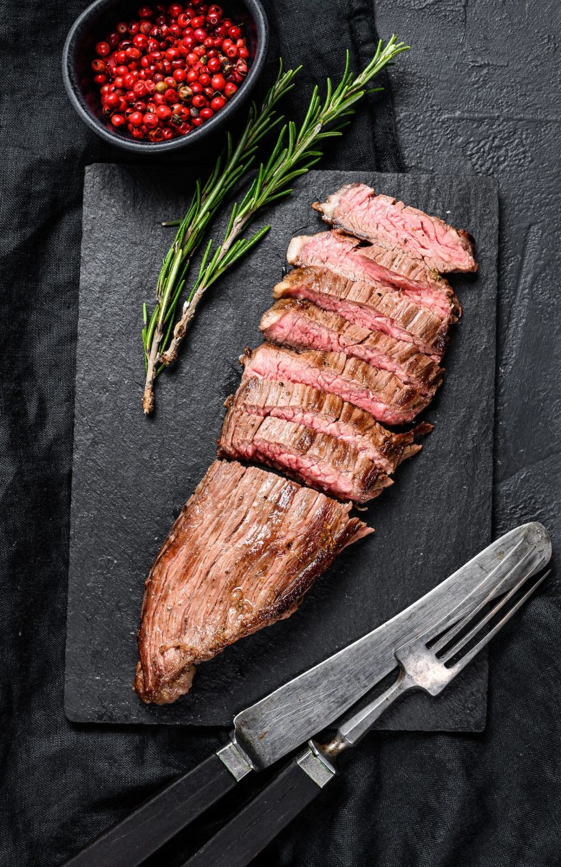 grill-restaurant-beef-menu-flank-steak-on-a-black-stone-board-black-background-top-view.jpg